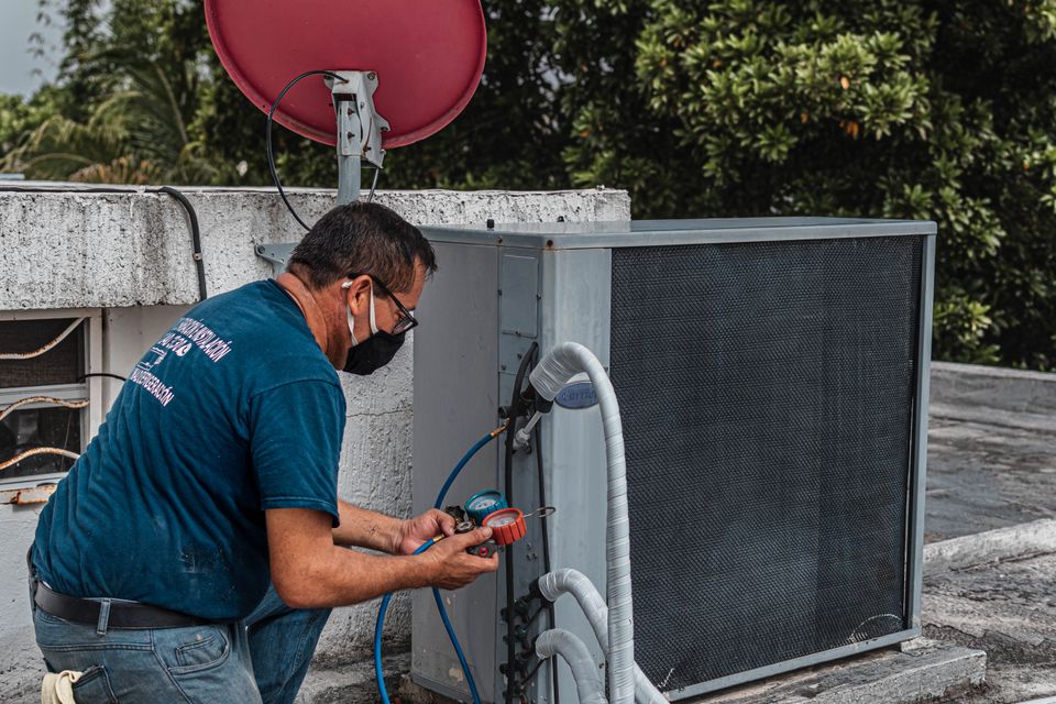 Stock view of an HVAC technician checking an outdoor air-conditioning unit